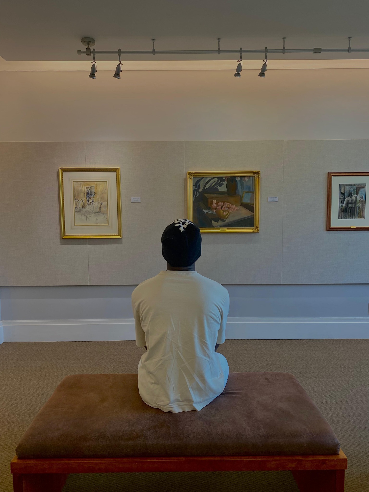 Person sitting on a bench viewing an artwork in an art museum